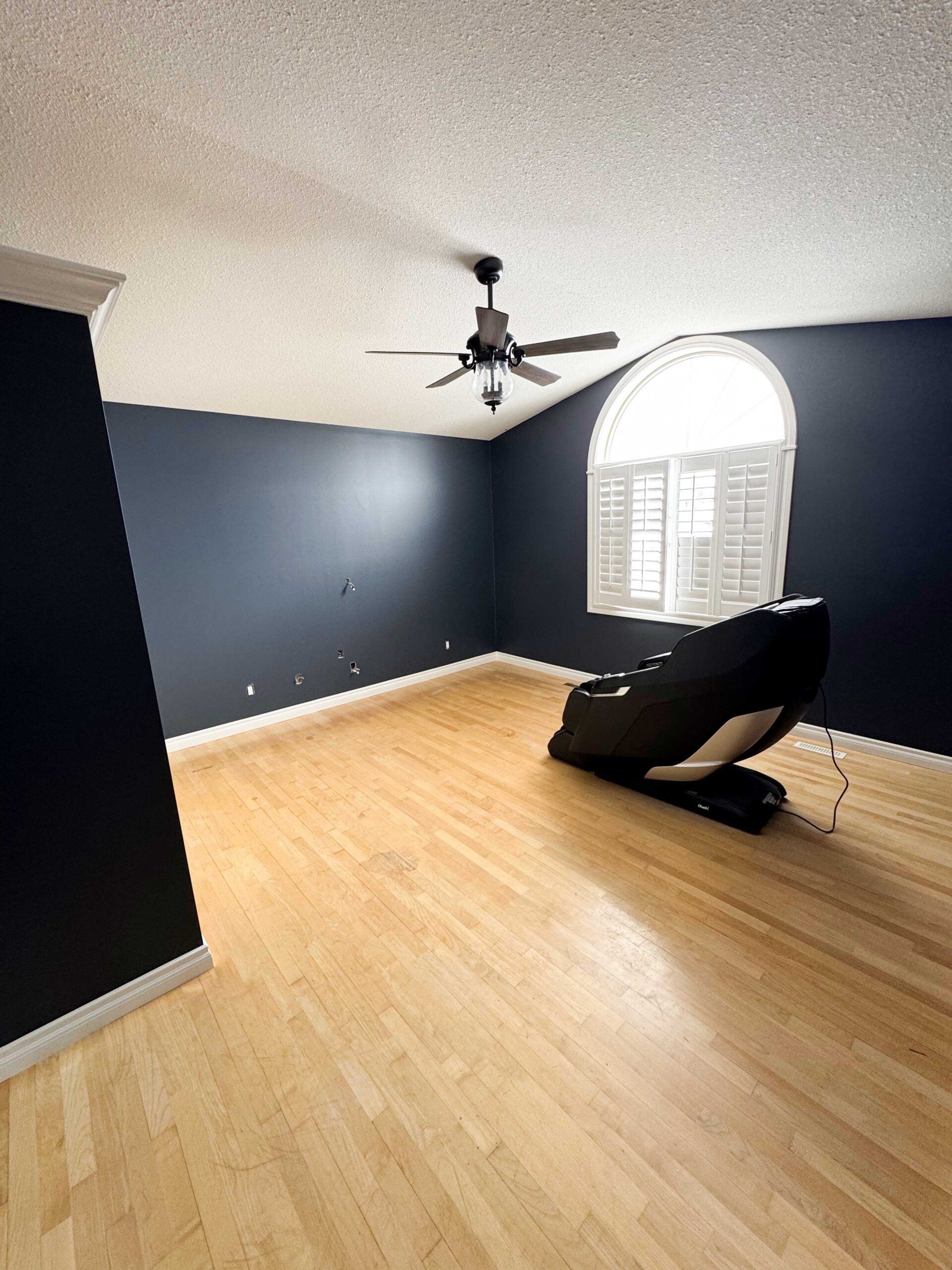 Modern bedroom featuring a professionally painted navy blue accent wall in a Calgary home.