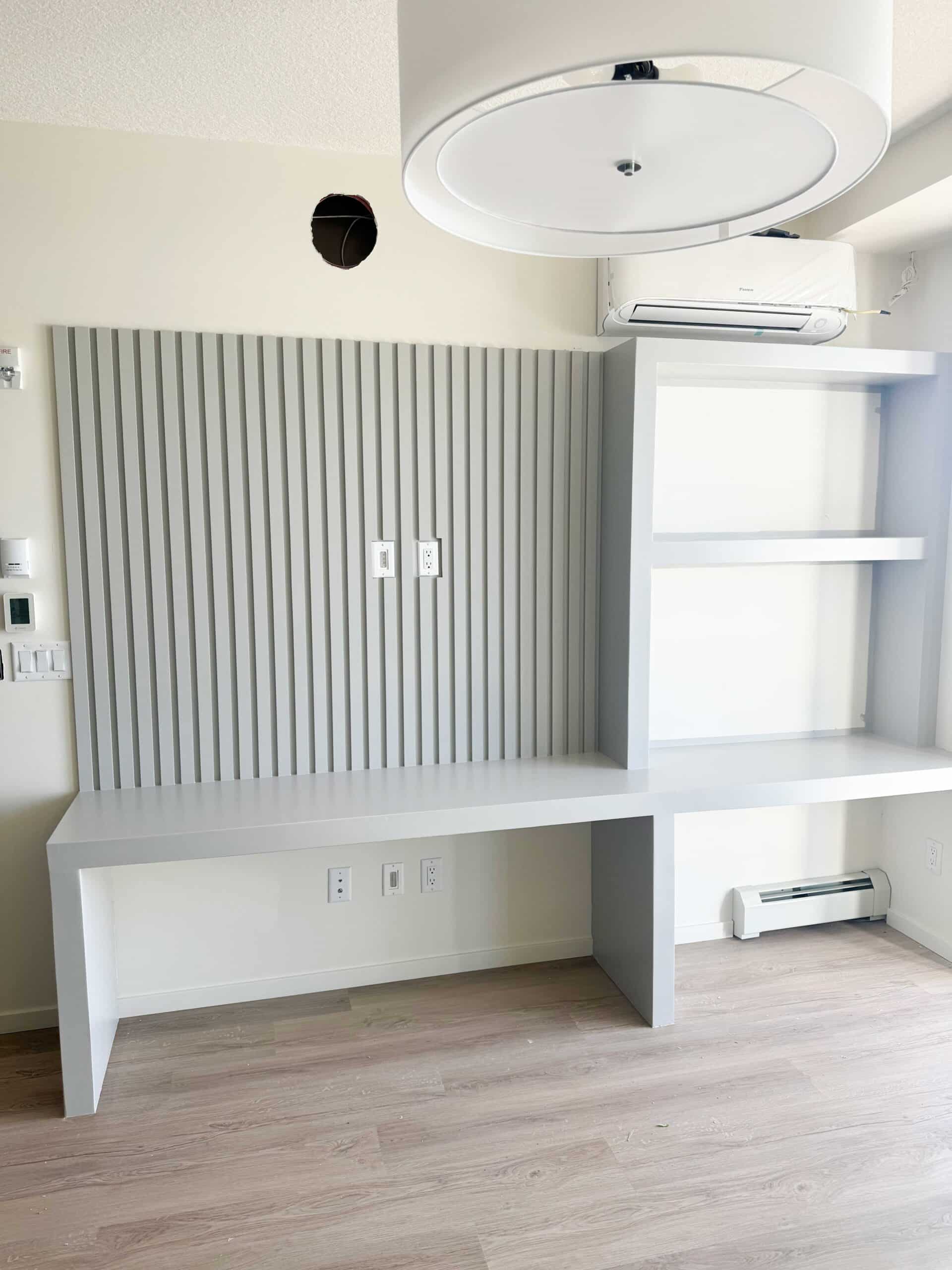 Custom built-in desk with decorative slat feature wall professionally painted in a Calgary home.