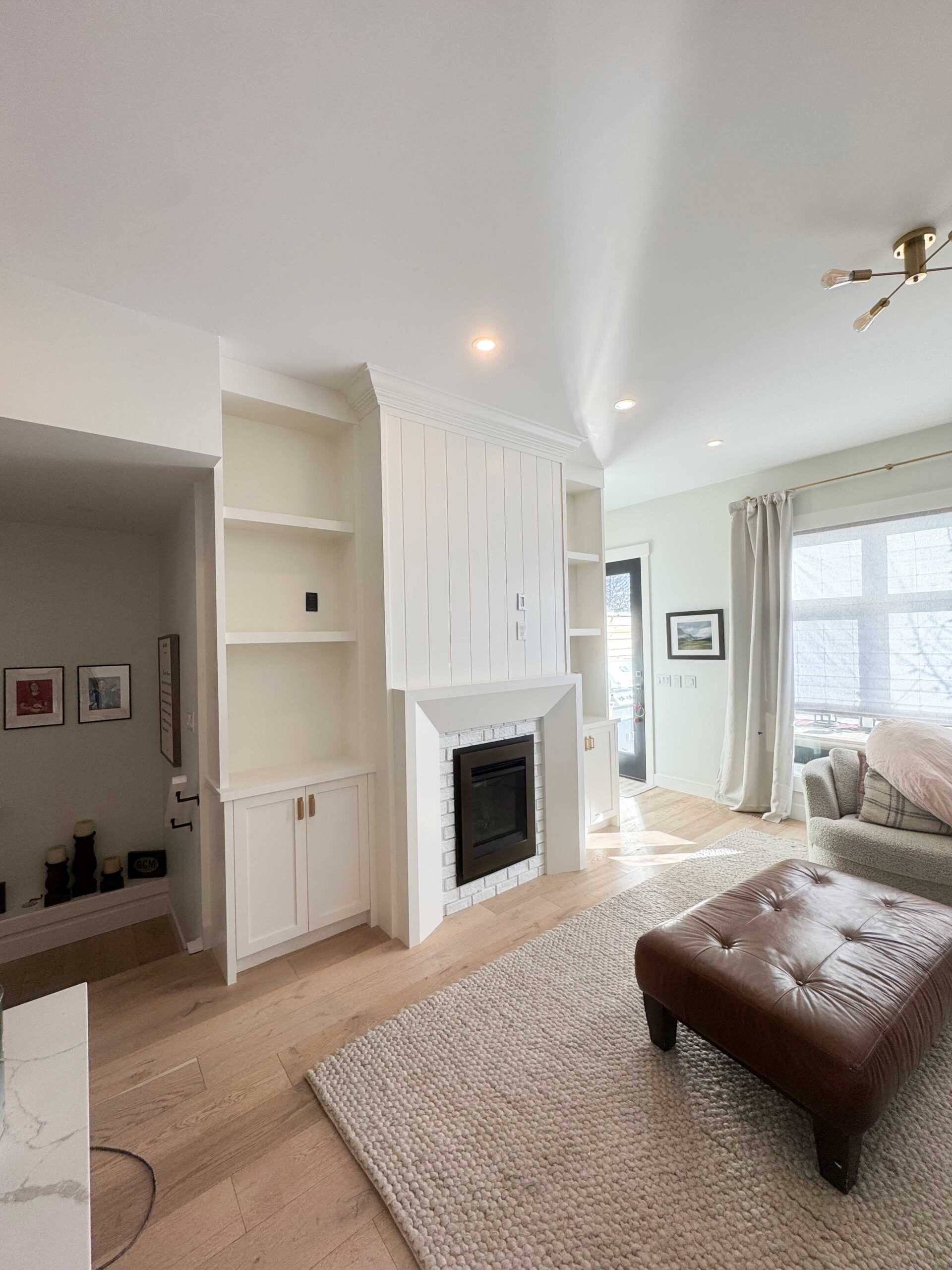 Bright living room with custom built-ins and a professionally painted fireplace feature wall in a Calgary home.