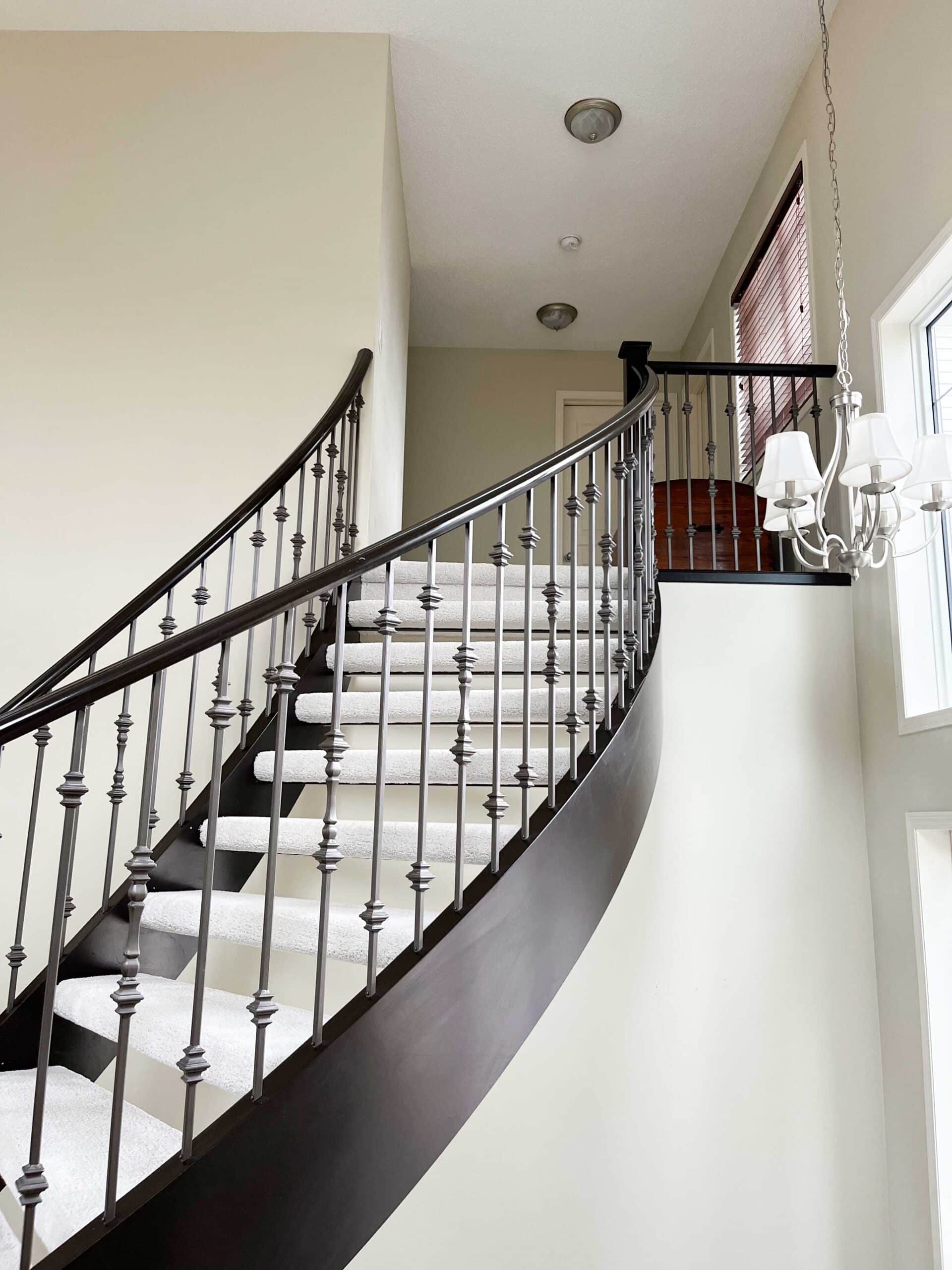 Elegant curved staircase with professionally painted walls, trim, and railings in a Calgary home.
