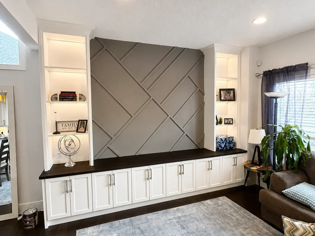 Custom built-in white cabinets with a geometric gray accent wall, illuminated display shelves, and a modern living room in a Calgary home.