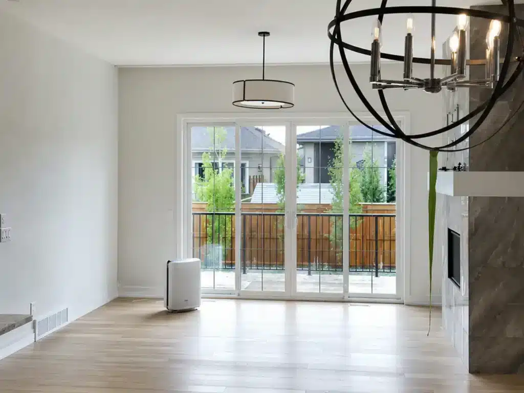 Modern open-concept living room with freshly painted white walls, high ceilings, recessed lighting, and large patio sliding doors.